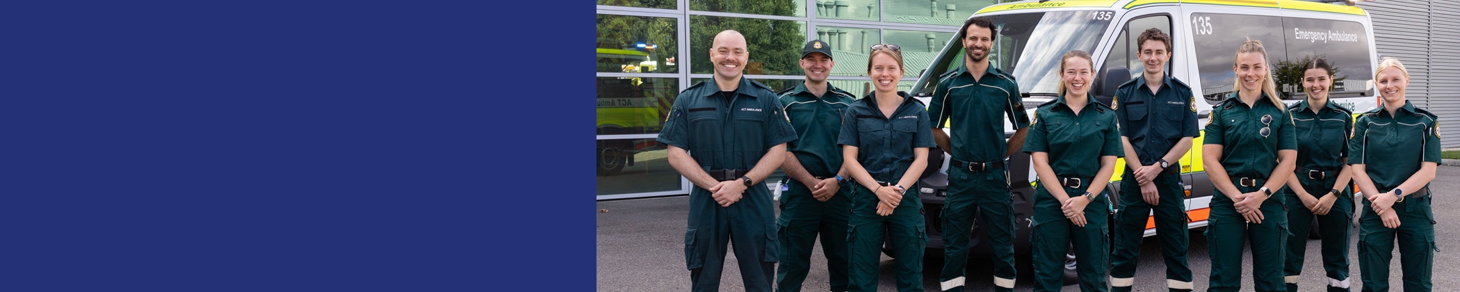 A group of ambulance staff in uniform posing for a photo in front of an ambulance